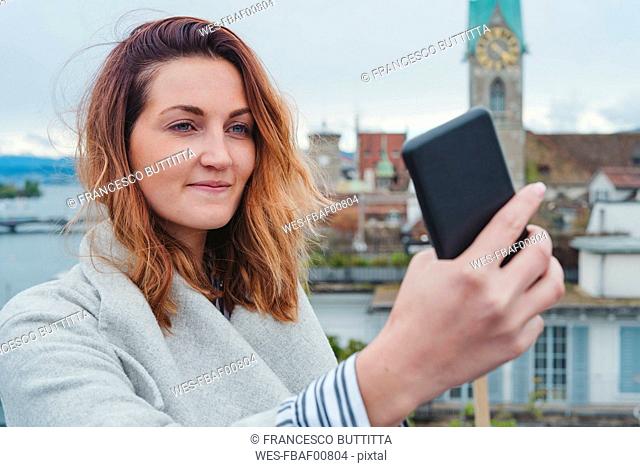 Young woman taking smartphone picture in the city, Zurich, Switzerland