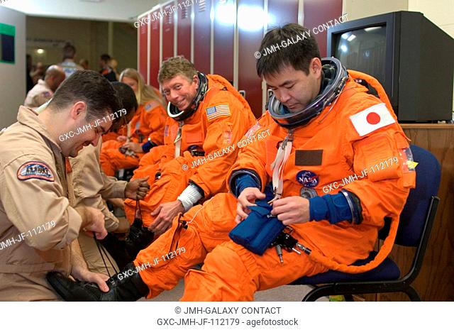 Japan Aerospace Exploration Agency (JAXA) astronaut Akihiko Hoshide (right), STS-124 mission specialist, dons a training version of his shuttle launch and entry...