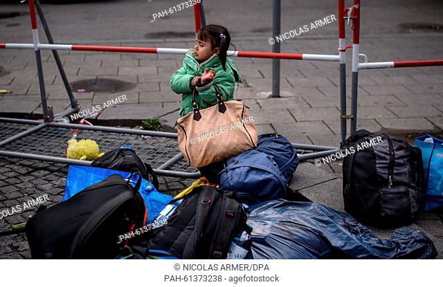 Littel girl Jara from Syria, who had arrived with her family by train, tries to lift a heavy travel bag at the central station in Munich, Germany