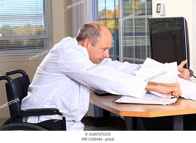 Man with Friedreich's Ataxia and deformed hands as a doctor looking at patient records at his computer