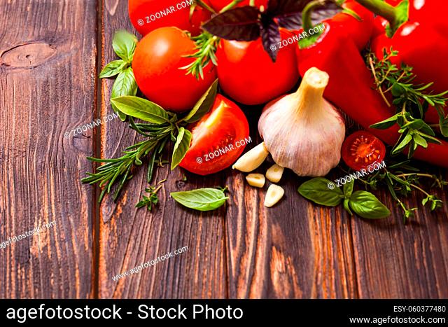 Closeup of various fresh vegetables together with fragrant herbs arranged and on the wooden background with place for copyspace