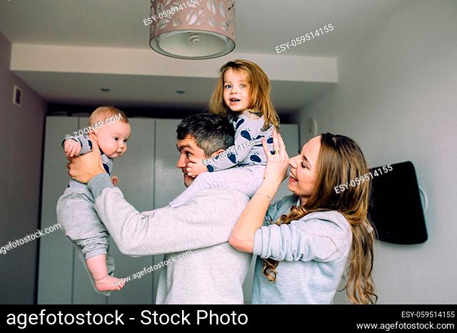 Portrait of happy young family playing on bed in the bedroom