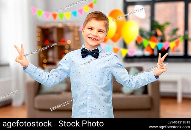 little boy in bowtie showing peace gesture