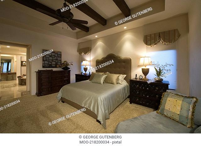 Silk bed cover on double bed in Palm Spring bedroom with beamed ceiling