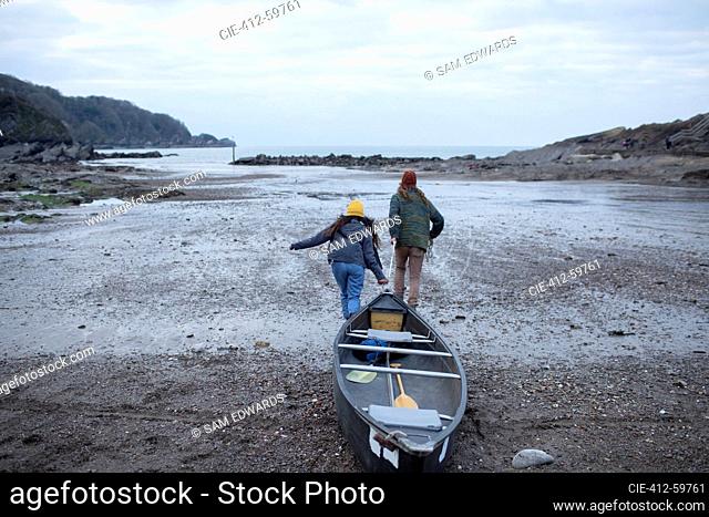 Couple pulling canoe on beach