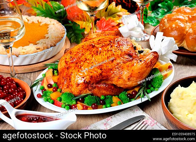 Baked turkey with vegetables, pumpkin pie, mashed potatoes, garlic buns and cranberry-orange sauce on the table dinner on Thanksgiving Day