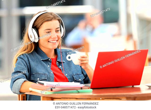 Single relaxed student female watching and listening media content on line sitting in a coffee shop