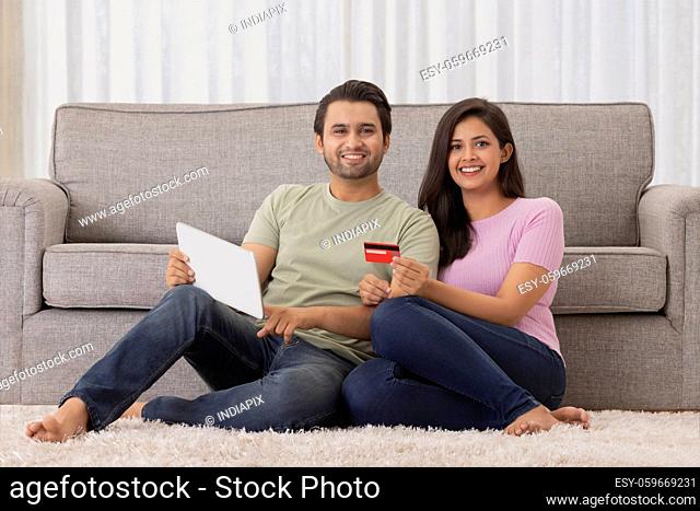 A young man and woman making online payment with credit card and tab in their room