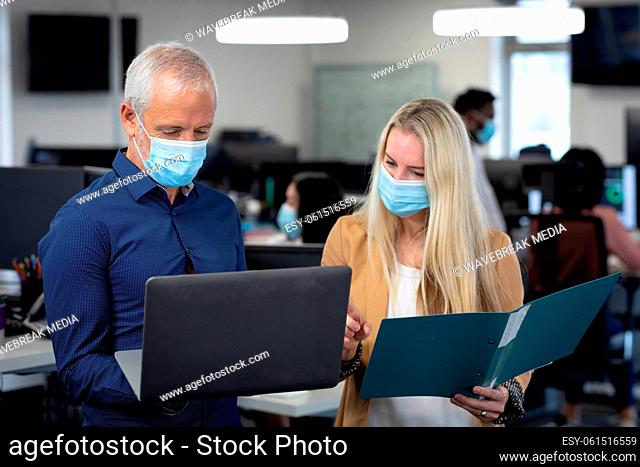 Senior businessman and businesswoman wearing face masks working together at modern office