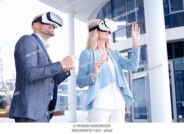 Man and woman wearing virtual reality glasses outdoors