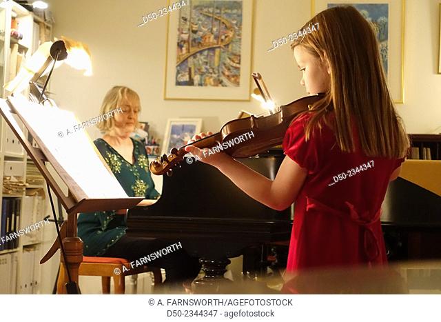 Young girl at violin recital with teacher on piano, Stockholm, Sweden