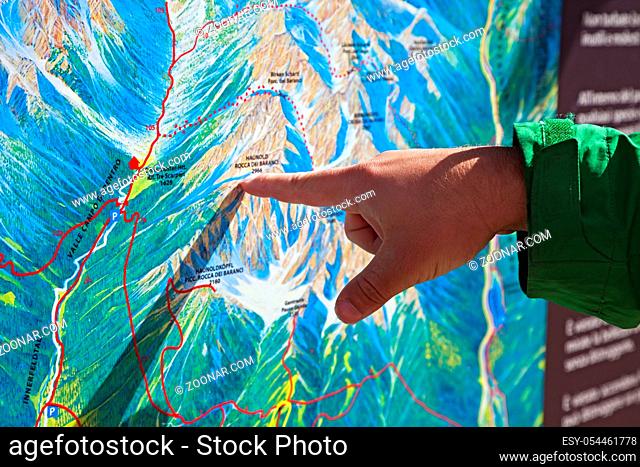 Finger pointing on a trekking map of an area in Dolomites, Northern Italy