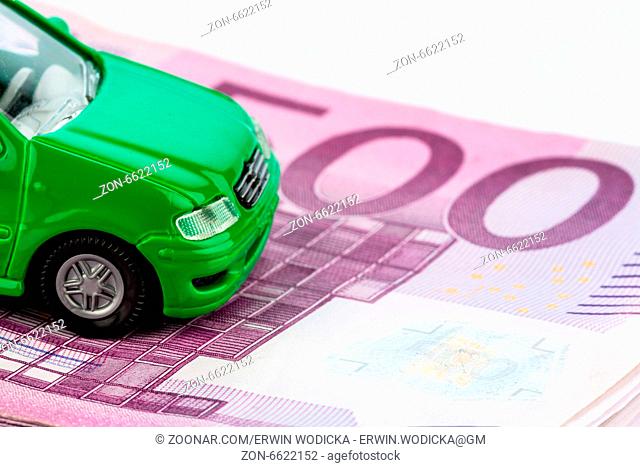 Grünes Modellauto auf Geldscheinen, Symbolfoto für Autokauf, Finanzierung und Kosten