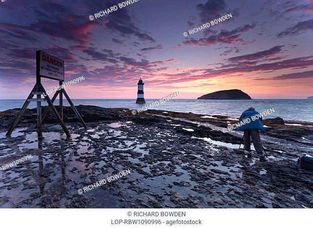 Wales, Anglesey, Penmon, A photographer photographing Penmon Lighthouse and Puffin Island at sunrise