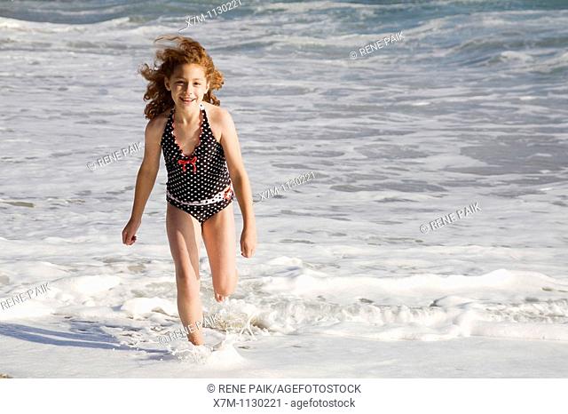 Young girl happily running through the ocean surf in Santa Cruz, California