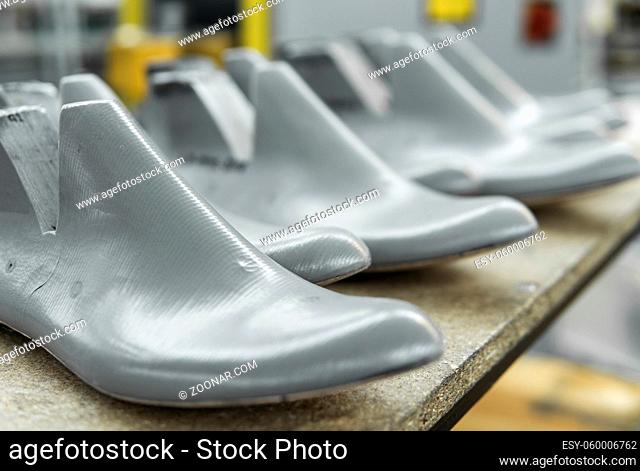 Plastic lasts used in the manufacture of shoes. Row of plastic shoe lasts used to manufacture modern day shoes. A lot of plastic last shoe on a wooden shelf