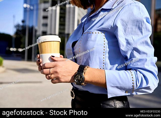 Female professional with bamboo coffee cup on street during sunny day