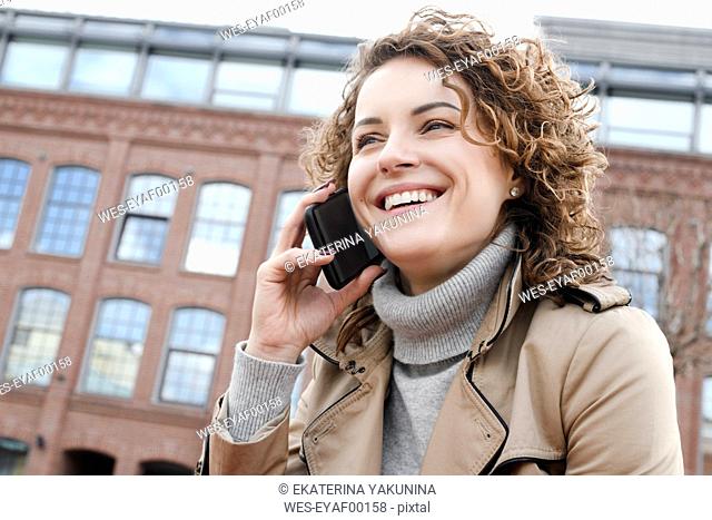 Portrait of happy woman with curly hair on the phone