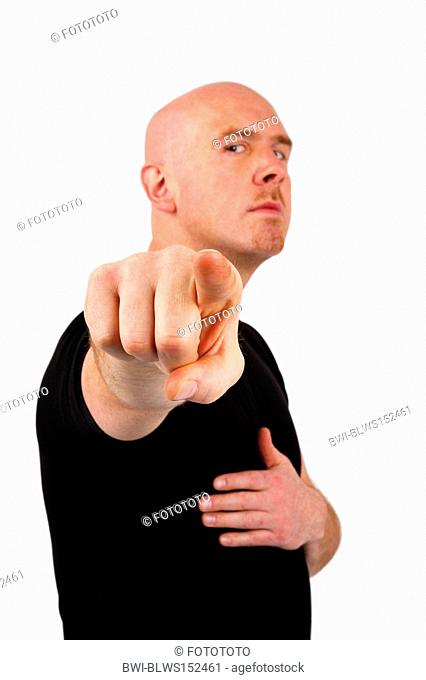 bald headed, young mean man is pointing with his finger into the camera
