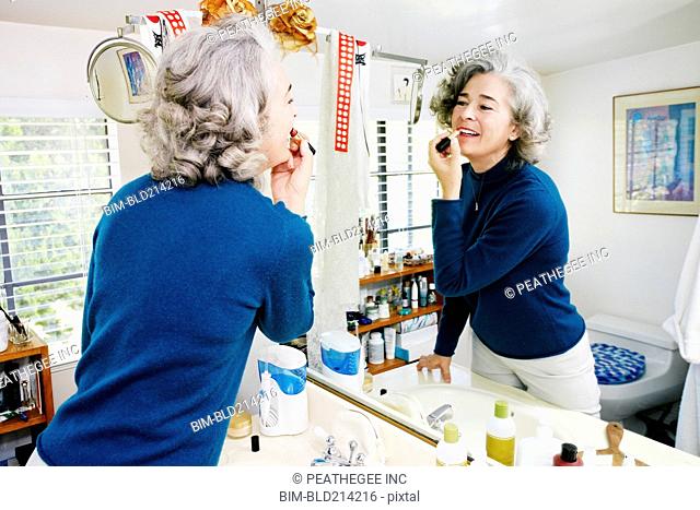 Caucasian woman applying makeup in mirror
