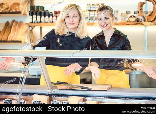 Two friendly salesladies at the cheese counter offering their goods
