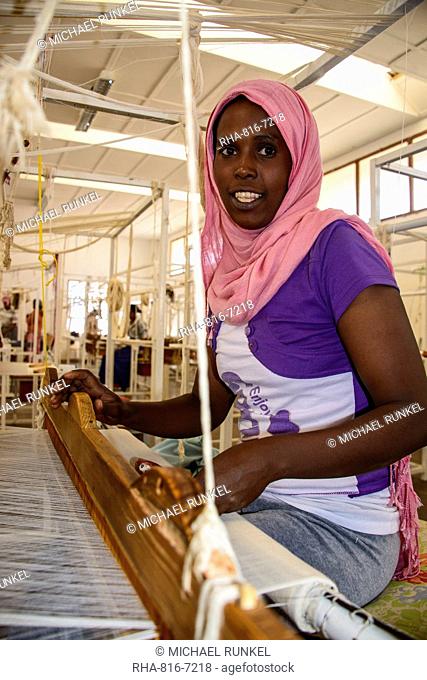 Friendly woman working on a hand weaving loom on a social project in the highlands of Eritrea, Africa