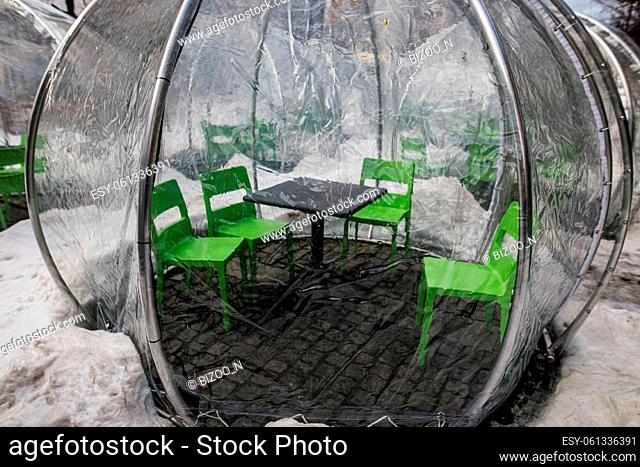View of a clear plastic bubble tent over a table set outside on the street to dine outdoors at a restaurant