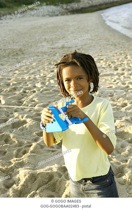 Young African boy flying a kite on beach