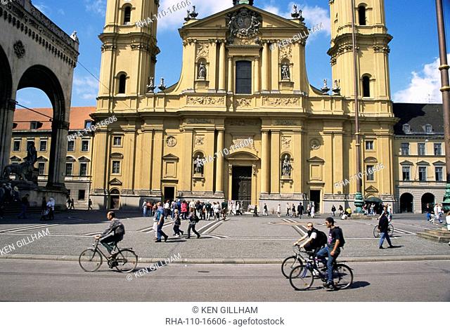 Cyclists passing the Theatinerkirche church, Munich, Bavaria, Germany, Europe