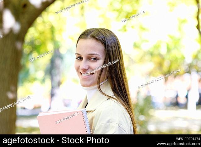 Smiling woman with book in college park