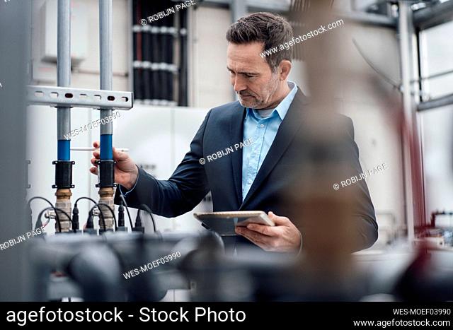 Businessman with tablet PC analyzing machinery in greenhouse