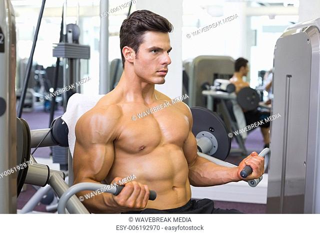 Determined muscular man working on abdominal machine