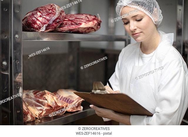 Woman with clipboard in storehouse of a butchery