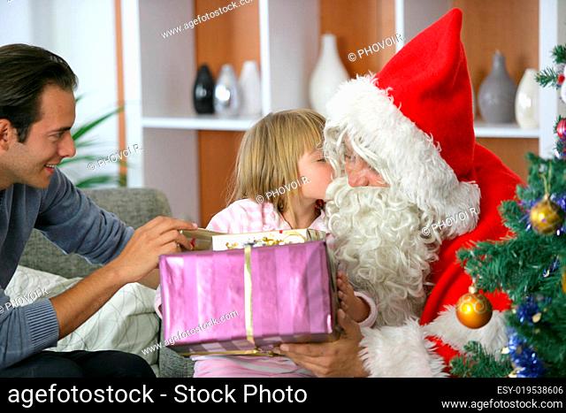 Girl kissing on the cheek Father Christmas with gifts in their hands