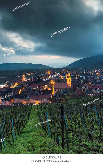Clouds and lights on the old town of Riquewihr framed by green vineyards, Colmar, Haut-Rhin department, Alsace, France, Europe