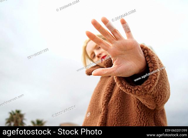 Outdoor portrait of young woman covers her face with hands. High quality photo