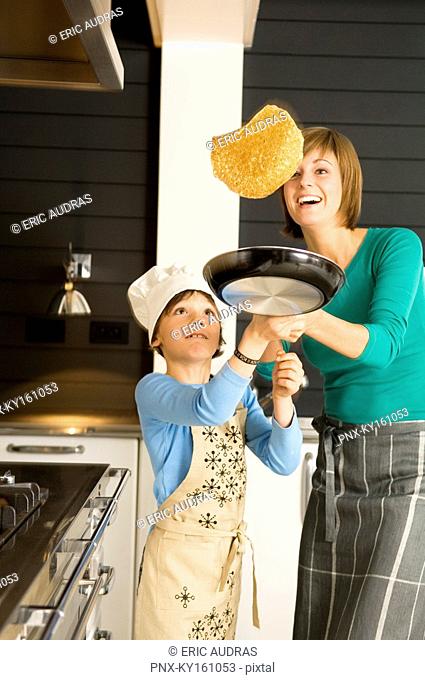 Young woman flipping a pancake with her son