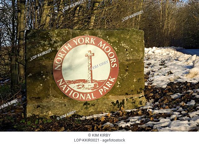 England, North Yorkshire, North York Moors, Fallen leaves and snow on the ground beside a North York Moors National Park sign