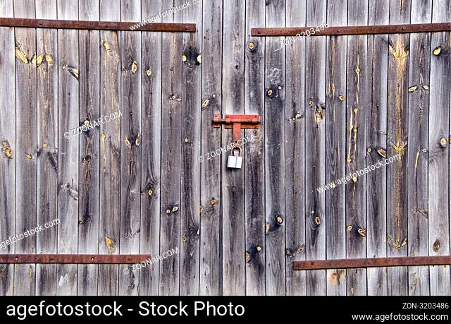 Old wooden farm rural building doors locked with padlock. Background of old architecture