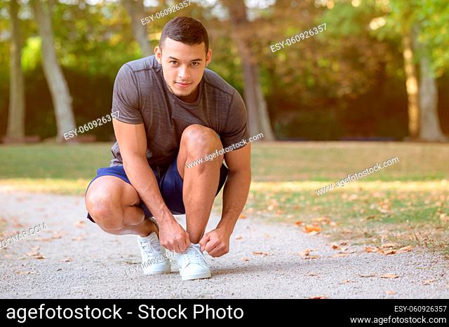 Young latin man tying lace shoelace shoes runner ready preparing start running jogging sports training fitness outdoor