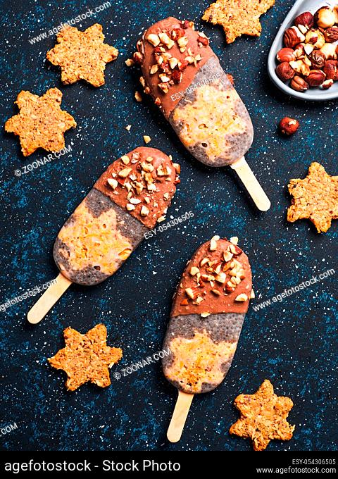 Chia popsicle with raw carrot cake and chocolate on dark blue background. Healthy recipe and idea homemade vegan popsicle ice cream