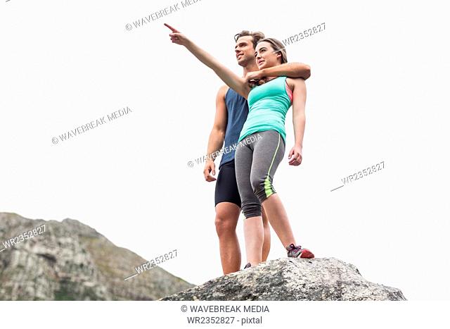 Woman pointing while man standing on rock