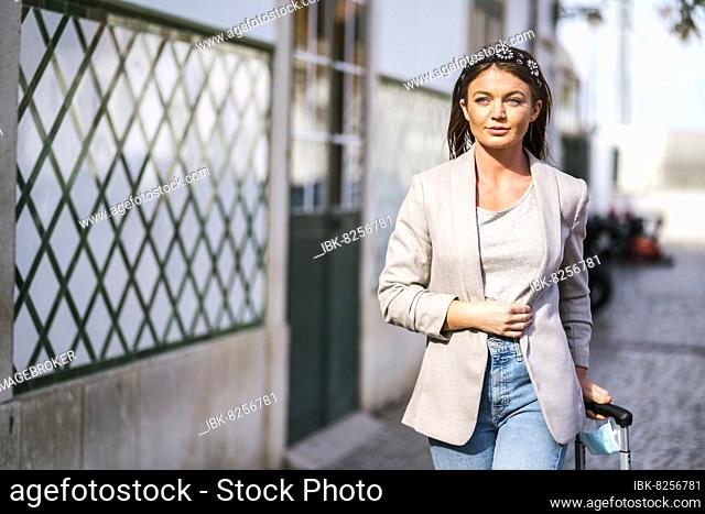Portrait of traveling woman with suitcase in urban settings