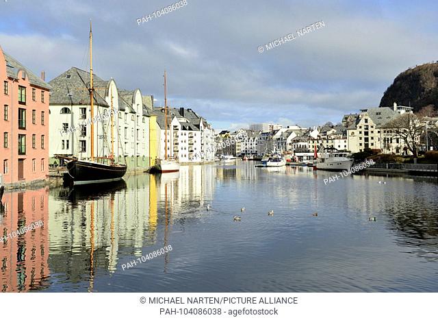 Ålesund's inner harbour with reflecting boats and ships and buildings at the waterside and the mountain Aksla at the side, 3 March 2017 | usage worldwide