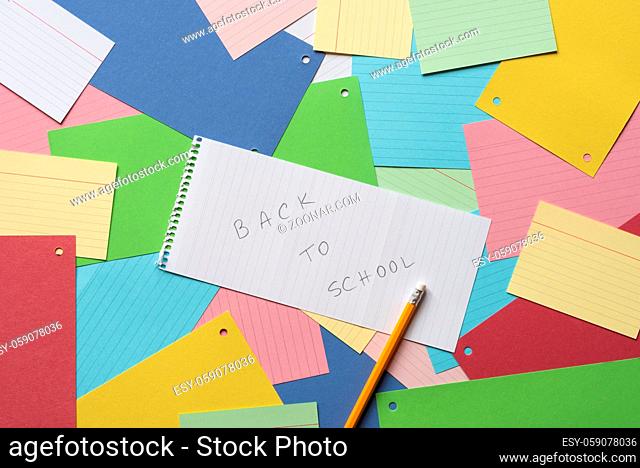 Notebook sheet with the message back to school against a background of colorful paper notes