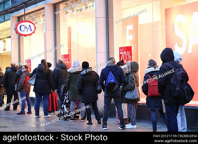 15 December 2020, Hamburg: People line up outside a department store advertising discounted merchandise the afternoon before the lockdown