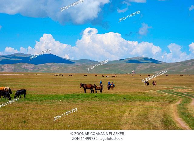 Riders riding towards caravanserai by Song Kul lake, Kyrgyzstan