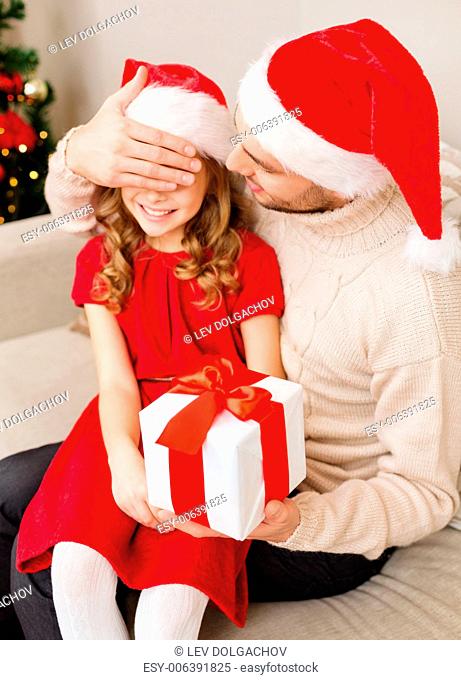 family, christmas, xmas, happiness and people concept - smiling father surprise daughter with gift box covering eyes with hand