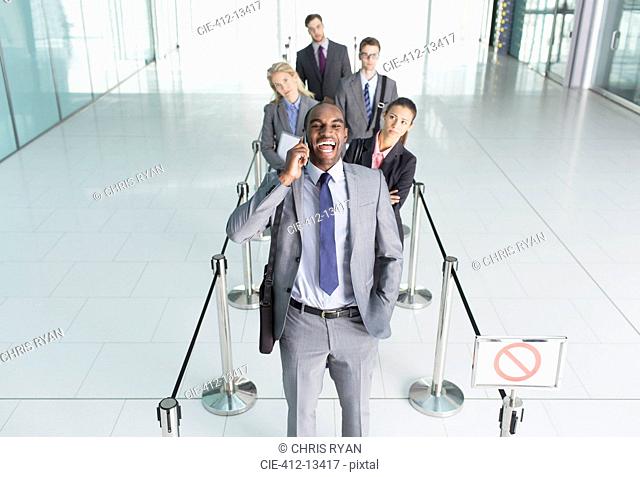 Businessman talking on cell phone in line