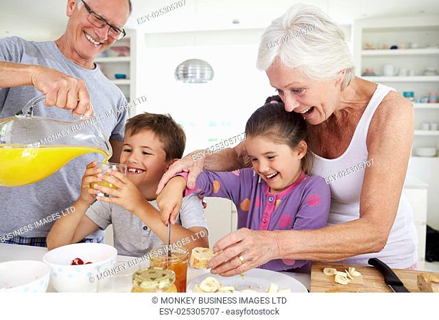 Grandparents With Grandchildren Making Breakfast In Kitchen